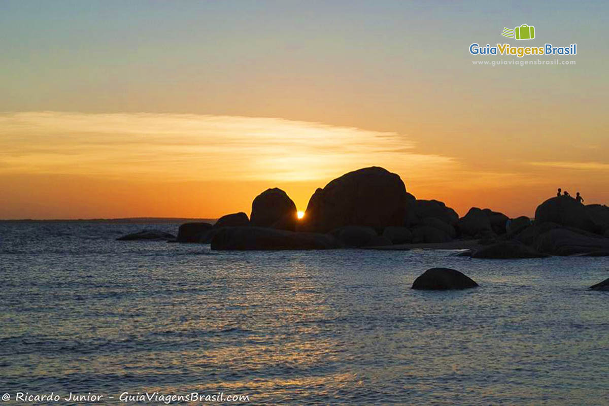 Imagem do sol se pondo no horizonte e o belo mar da Praia Pedra do Sal.